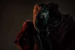 The Creature, swathed in furs, with a good and a mask over his face, looks to the side in Guillermo del Toro's Frankenstein
